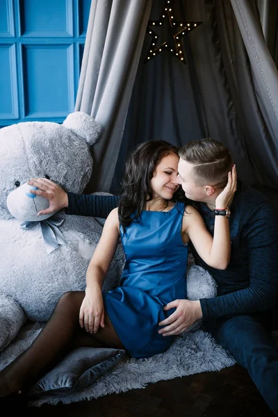 Junges fröhliches europäisches verliebtes Paar, das sich umarmt und küsst, in einem mit Herzen dekorierten Studio am Valentinstag, Datierung. — Stockfoto