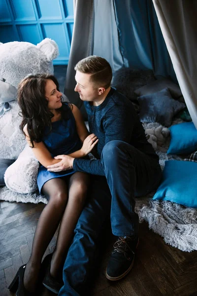 Junges fröhliches europäisches verliebtes Paar, das sich umarmt und küsst, in einem mit Herzen dekorierten Studio am Valentinstag, Datierung. — Stockfoto