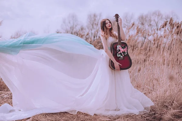 Bella romantica ragazza europea con chitarra con fiori all'interno, in posa all'aperto. Concetto di musica e natura. Tempo primaverile . — Foto Stock