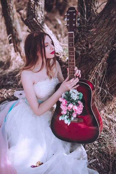아름다운 유럽 소녀가 기타를 들고 꽃을 안에 꽂고 야외에 포즈를 취합니다. 음악 과 자연의 개념. 봄 시간. — 스톡 사진