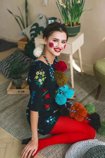 Menina morena bonita na moda em um macacão com bordado floral com maquiagem a cores: bochechas vermelhas e lábios. Avó estilo chique. Retrato retocado — Fotografia de Stock