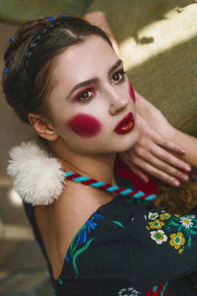 Modieuze mooie brunette meisje in een jumpsuit met bloemen borduurwerk met kleur make-up: rode wangen en lippen. Oma chique stijl. Geretoucheerde portret — Stockfoto