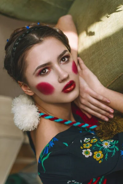 Menina morena bonita na moda em um macacão com bordado floral com maquiagem a cores: bochechas vermelhas e lábios. Avó estilo chique. Retrato retocado — Fotografia de Stock