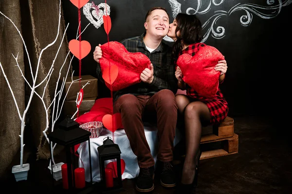 Joven pareja europea alegre en el amor abrazar y besar, en decorado con corazones estudio en día de San Valentín, citas . —  Fotos de Stock