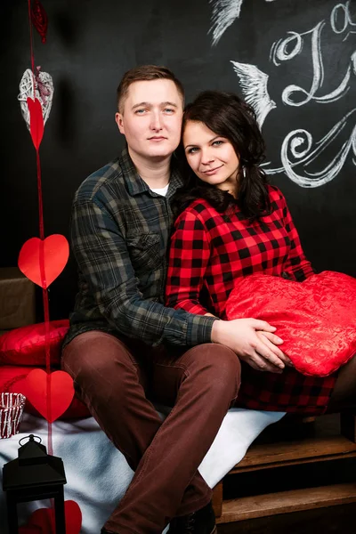 Joven pareja europea alegre en el amor abrazar y besar, en decorado con corazones estudio en día de San Valentín, citas . —  Fotos de Stock