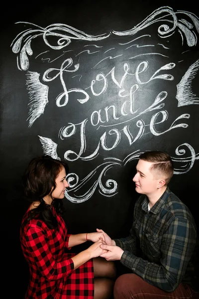 Joven pareja europea alegre en el amor abrazar y besar, en decorado con corazones estudio en día de San Valentín, citas . —  Fotos de Stock