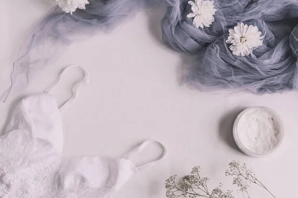 Düz moda blog ve sosyal medya için yatıyordu. Kadının glamour beyaz ve bej beyaz bir arka plan üzerinde güzellik aksesuarları. İç çamaşırı, mücevher, parfüm, krem, sabun, külot, uyku maskesi, sarmal saç bağları. C