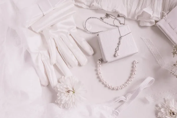 White bridal accessories for wedding background with pearls, white satin ribbons and lace, gloves, bracelet,flat lay for fashion blog, top view