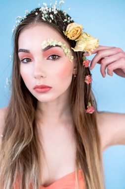 Kozmetik ve manikür. Yakın çekim portre olan kuru çiçekler onun yüz ve saç, pastel renkli, çekici kadın makyaj mükemmel ve mavi arka plan üzerinde deri. Taze, trendy, Bahar düzeltisiz portre