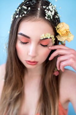 Kozmetik ve manikür. Yakın çekim portre olan kuru çiçekler onun yüz ve saç, pastel renkli, çekici kadın makyaj mükemmel ve mavi arka plan üzerinde deri. Taze, trendy, Bahar düzeltisiz portre