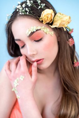 Kozmetik ve manikür. Yakın çekim portre olan kuru çiçekler onun yüz ve saç, pastel renkli, çekici kadın makyaj mükemmel ve mavi arka plan üzerinde deri. Taze, trendy, Bahar düzeltisiz portre