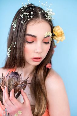 Kozmetik ve manikür. Yakın çekim portre olan kuru çiçekler onun yüz ve saç, pastel renkli, çekici kadın makyaj mükemmel ve mavi arka plan üzerinde deri. Taze, trendy, Bahar düzeltisiz portre