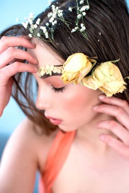 Kozmetik ve manikür. Yakın çekim portre olan kuru çiçekler onun yüz ve saç, pastel renkli, çekici kadın makyaj mükemmel ve mavi arka plan üzerinde deri. Taze, trendy, Bahar düzeltisiz portre