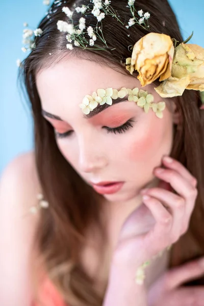 Kozmetik ve manikür. Yakın çekim portre olan kuru çiçekler onun yüz ve saç, pastel renkli, çekici kadın makyaj mükemmel ve mavi arka plan üzerinde deri. Taze, trendy, Bahar düzeltisiz portre
