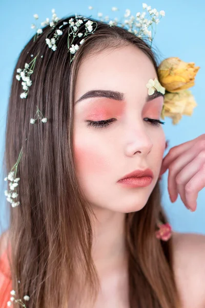 Kozmetik ve manikür. Yakın çekim portre olan kuru çiçekler onun yüz ve saç, pastel renkli, çekici kadın makyaj mükemmel ve mavi arka plan üzerinde deri. Taze, trendy, Bahar düzeltisiz portre