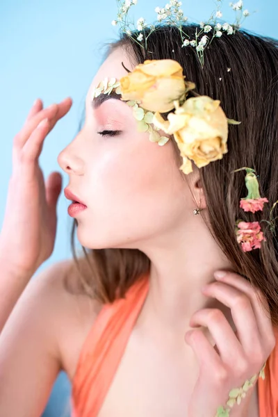 Cosmetici e manicure. Ritratto ravvicinato di donna attraente con fiori secchi sul viso e sui capelli, colore pastello, trucco perfetto e pelle su sfondo blu. Ritocco fresco, alla moda, ritocco primaverile — Foto Stock