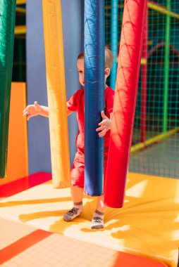 Gülen çocuk 1-2 yaşında, çocuk parkında ve oyun merkezinde doğum günü partisinde top havuzunda eğleniyor. Çocuk oyun parkında renkli toplarla oynuyor. Küçük çocuk için oyuncaklar.