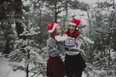 İki genç yeniyetme kız arkadaş bir arada. İki kız kardeşin moda portresini yakın çekin. Kışları eğlenin, süveter giyin, en iyi arkadaşlar açık havada, karlı havada.