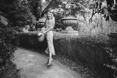 Şehvetli genç sarışın güzel ve zarif bir kadın kayaya oturmuş Çin 'deki tropik yeşil orman palmiyesinden kameraya bakıyor..