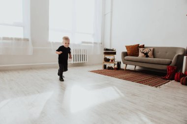 İki yaşındaki havalı hippi çocuk, sonbahar dekorunun süslü fotoğraf sahasında güzel, parlak sonbahar yapraklarıyla poz veriyor. Sıcak atmosfer