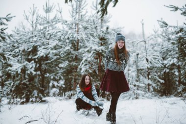 İki genç yeniyetme kız arkadaş bir arada. İki kız kardeşin moda portresini yakın çekin. Kışları eğlenin, süveter giyin, en iyi arkadaşlar açık havada, karlı havada.