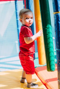 Gülen çocuk 1-2 yaşında, çocuk parkında ve oyun merkezinde doğum günü partisinde top havuzunda eğleniyor. Çocuk oyun parkında renkli toplarla oynuyor. Küçük çocuk için oyuncaklar.