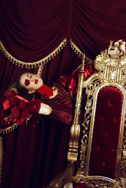 Kupa kızı gibi giyinmiş bir kadın, büyük bir yüreği olan yaratıcı bir makyaj, tahtta oturan bir kız, son rötuşlu bir portre. Kavramsal fotoğraf