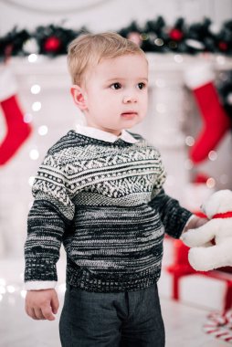 Genç bir çocuğun Noel portresi şöminenin ve Noel ağacının etrafında rahat bir atmosfer.