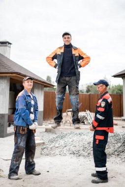 İş, inşaat, takım çalışması ve insanların konsepti - açık havada gülen inşaatçılar grubu