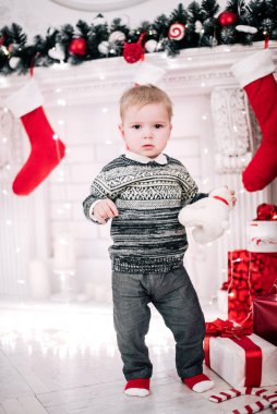 Genç bir çocuğun Noel portresi şöminenin ve Noel ağacının etrafında rahat bir atmosfer.