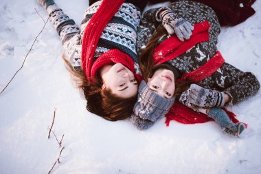 İki genç yeniyetme kız arkadaş bir arada. İki kız kardeşin moda portresini yakın çekin. Kışları eğlenin, süveter giyin, en iyi arkadaşlar açık havada, karlı havada.