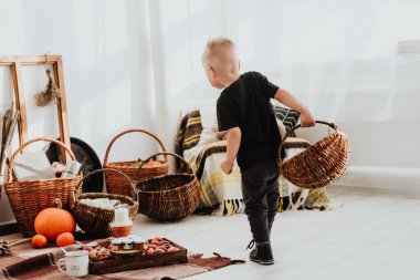 İki yaşındaki havalı hippi çocuk, sonbahar dekorunun süslü fotoğraf sahasında güzel, parlak sonbahar yapraklarıyla poz veriyor. Sıcak atmosfer