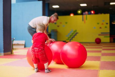 Mutlu gülen çocuk. 1-2 yaşında. Çocuk parkında ve oyun merkezinde büyükbabasıyla eğleniyor.. 