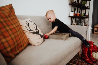 İki yaşındaki havalı hippi çocuk, sonbahar dekorunun süslü fotoğraf sahasında güzel, parlak sonbahar yapraklarıyla poz veriyor. Sıcak atmosfer