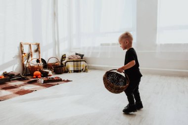 İki yaşındaki havalı hippi çocuk, sonbahar dekorunun süslü fotoğraf sahasında güzel, parlak sonbahar yapraklarıyla poz veriyor. Sıcak atmosfer