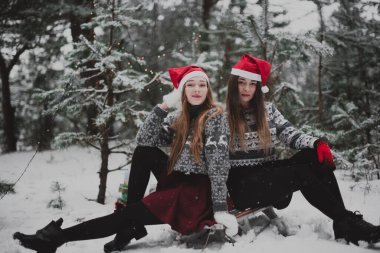 İki genç yeniyetme kız arkadaş bir arada. İki kız kardeşin moda portresini yakın çekin. Kışları eğlenin, süveter giyin, en iyi arkadaşlar açık havada, karlı havada.