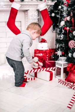 Genç bir çocuğun Noel portresi şöminenin ve Noel ağacının etrafında rahat bir atmosfer.