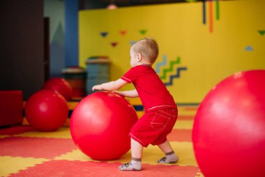 Gülen çocuk 1-2 yaşında, çocuk parkında ve oyun merkezinde doğum günü partisinde top havuzunda eğleniyor. Çocuk oyun parkında renkli toplarla oynuyor. Küçük çocuk için oyuncaklar.