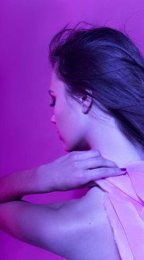 Pembe kurdeleli uzun kıvırcık saçlı güzel, modaya uygun bir kız. Stüdyodaki pembe arka plandaki kız. Moda, güzellik. Parlak kıyafetler. Saç için makyaj malzemeleri, sağlıklı saçlar..