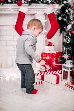Genç bir çocuğun Noel portresi şöminenin ve Noel ağacının etrafında rahat bir atmosfer.