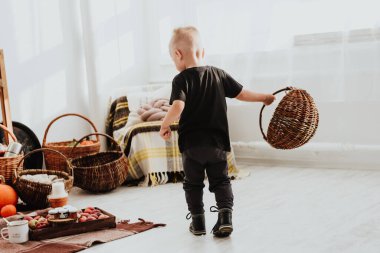 İki yaşındaki havalı hippi çocuk, sonbahar dekorunun süslü fotoğraf sahasında güzel, parlak sonbahar yapraklarıyla poz veriyor. Sıcak atmosfer