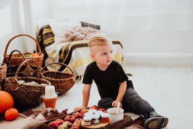 İki yaşındaki havalı hippi çocuk, sonbahar dekorunun süslü fotoğraf sahasında güzel, parlak sonbahar yapraklarıyla poz veriyor. Sıcak atmosfer