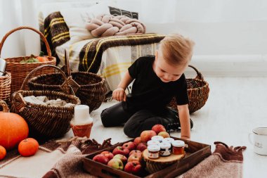 İki yaşındaki havalı hippi çocuk, sonbahar dekorunun süslü fotoğraf sahasında güzel, parlak sonbahar yapraklarıyla poz veriyor. Sıcak atmosfer