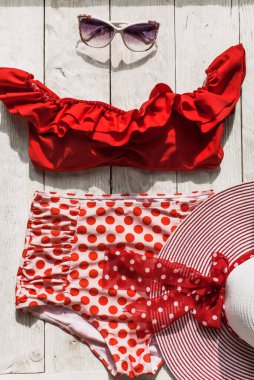 Beyaz ahşap arka planda dişi kırmızı retro mayo plaj aksesuarları. Düzlük, üst görünüm, yaz ve seyahat kavramı