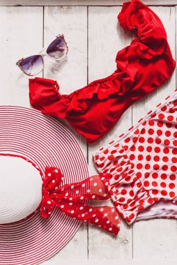 Beyaz ahşap arka planda dişi kırmızı retro mayo plaj aksesuarları. Düzlük, üst görünüm, yaz ve seyahat kavramı