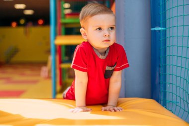 Gülen çocuk 1-2 yaşında, çocuk parkında ve oyun merkezinde doğum günü partisinde top havuzunda eğleniyor. Çocuk oyun parkında renkli toplarla oynuyor. Küçük çocuk için oyuncaklar.