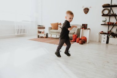 İki yaşındaki havalı hippi çocuk, sonbahar dekorunun süslü fotoğraf sahasında güzel, parlak sonbahar yapraklarıyla poz veriyor. Sıcak atmosfer