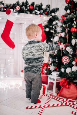 Genç bir çocuğun Noel portresi şöminenin ve Noel ağacının etrafında rahat bir atmosfer.