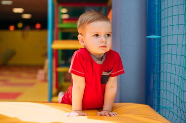 Gülen çocuk 1-2 yaşında, çocuk parkında ve oyun merkezinde doğum günü partisinde top havuzunda eğleniyor. Çocuk oyun parkında renkli toplarla oynuyor. Küçük çocuk için oyuncaklar.