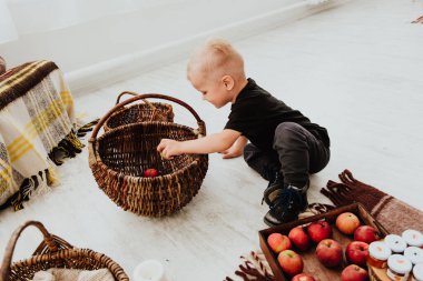 İki yaşındaki havalı hippi çocuk, sonbahar dekorunun süslü fotoğraf sahasında güzel, parlak sonbahar yapraklarıyla poz veriyor. Sıcak atmosfer